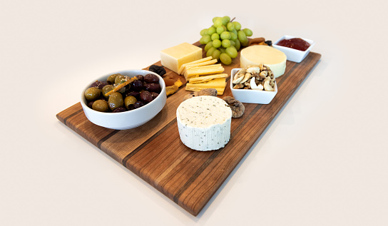 Delicious Cheese Assortment on a wooden board with fruit, nuts, jelly, and olives. Gourmet Charcuterie Arrangment.