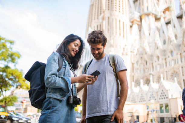 joven pareja turística mirando teléfono inteligente en barcelona - standing smiling two people 30s fotografías e imágenes de stock