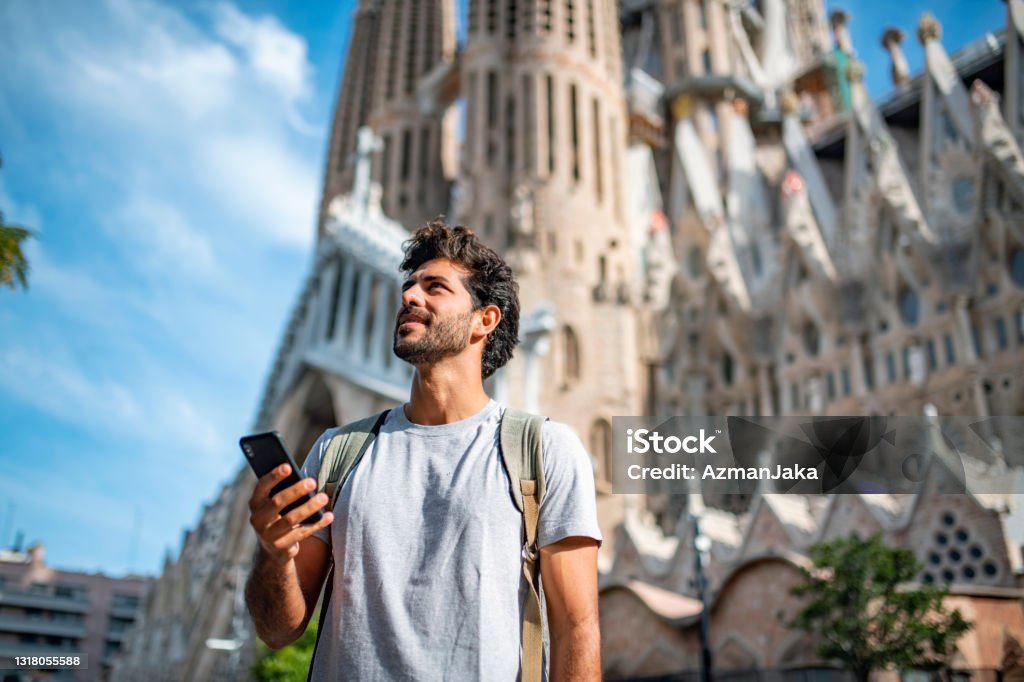 Mid Adult Male Tourist with Smart Phone in Barcelona Low angle view of 30 year old Hispanic male tourist using smart phone for sightseeing guidance with Sagrada Familia in background. Tourist Stock Photo