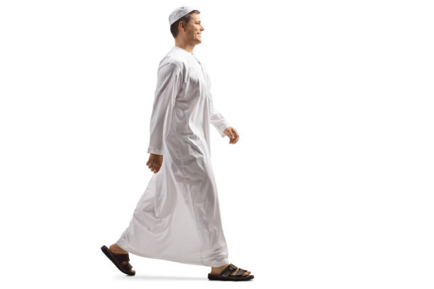 Full length profile shot of a young muslim man in white dishdasha walking Full length profile shot of a young muslim man in white dishdasha walking isolated on white background mullah photos stock pictures, royalty-free photos & images