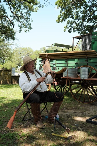 Reenactor senior man filling rifle with gunpowder at Texas Independence Day celebration at Acton, Texas, cemetery where Elizabeth Crockett, Davy's wife, is buried.