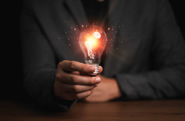 istock Businessman holding light bulb with orange rays , creative thinking idea and innovation concept. 1318069963