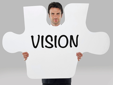 Businessman holding a missing piece of a puzzle with “Vision” text