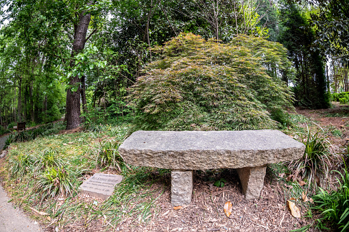 Spartanburg, S.C. - April 23, 2021:  View of a serene bench, natural stone seating, at the famous Hatcher Gardens, a beloved downtown landmark garden.