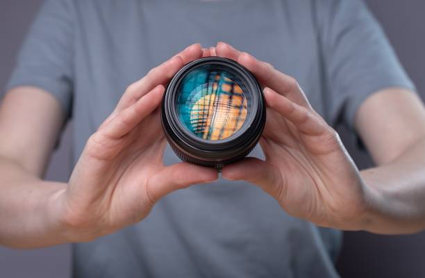 istock Modern digital camera lens with beautiful studio softbox reflection in hands of photographer 1318085621