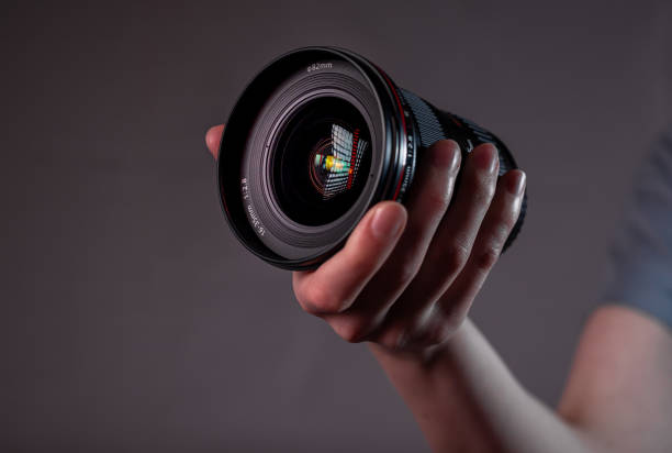 istock Modern digital camera lens in hand close up over dark background 1318085638