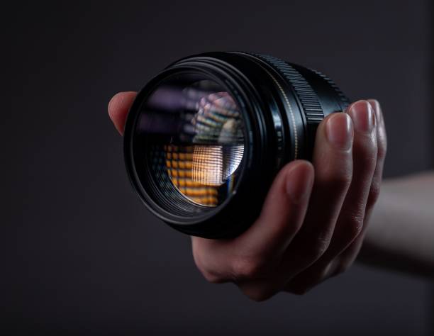 istock Modern digital camera lens in female hands over dark black grey background 1318085642