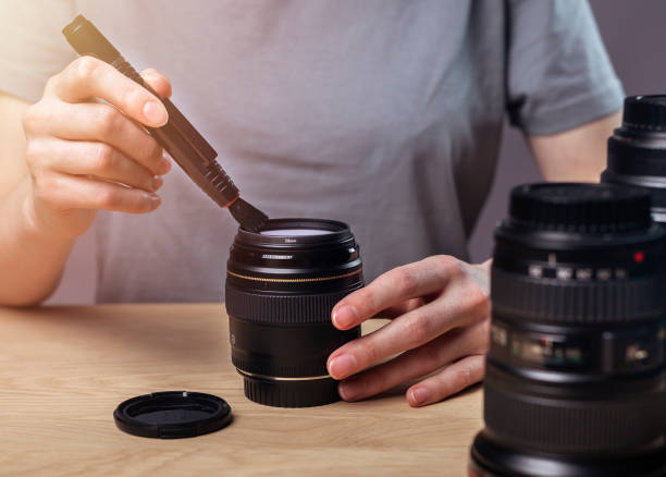 istock Female hands clean digital camera lens with professional brush, removing dust 1318085651