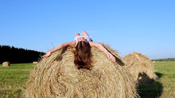 istock young female lies on a haystack and throws his hat. Rural area. freedom concept 1318090179