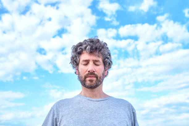istock man with his eyes closed with a sky in the background 1318094611