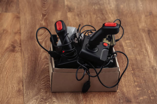 istock Cardboard Box with old wired joysticks and gamepads on a wooden floor 1318095655