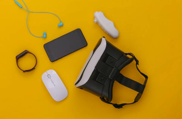 istock Modern gadgets and devices. Virtual reality headset with smartphone, controller, earphones, smart bracelet, pc mouse on yellow background. Top view. Flay lay 1318095687