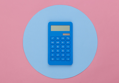 Calculator on pink background with a blue circle. Conceptual studio shot. Minimalism. Top view