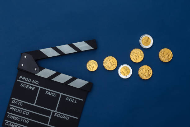 古典的な青の背景に映画のクラッパーボードとコイン。映画館の料金。映画製作、映画制作。トップビュー - nobody indoors cut out currency ストックフォトと画像