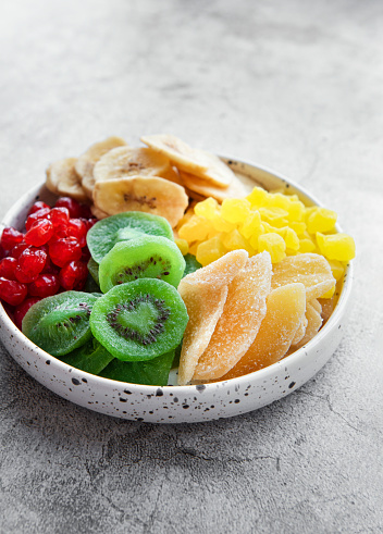 Bowl with various dried fruits  on a gray concrete background