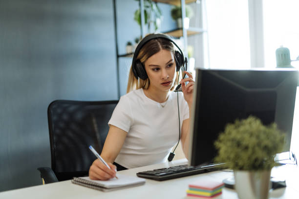 istock Young professional woman working in call centre on desktop pc with headphones 1318103277