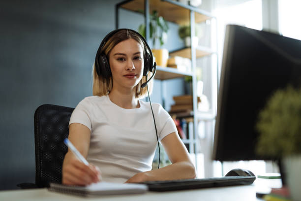 istock Young professional woman working in call centre on desktop pc with headphones 1318103456