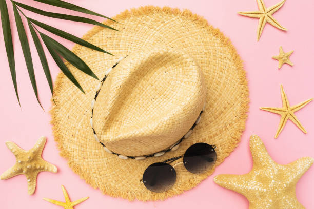 istock Womens straw hat, sunglasses, starfish and palm leaf on a pink background 1318108065
