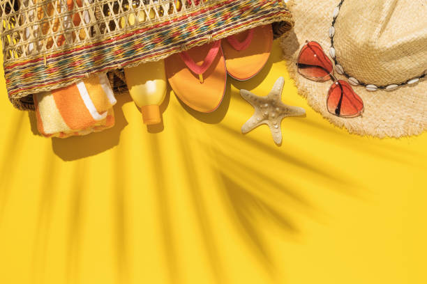 istock Straw bag with beach holiday accessories on yellow background and palm leaf shadow with copy space, summer background 1318108077