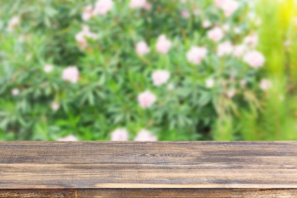 istock wood table top on blur bush with flowers background 1318110590