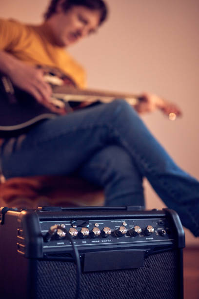 męski muzyk grający na gitarze akustycznej na wzmacniaczu w retro vintage roomie. - fingerstyle zdjęcia i obrazy z banku zdjęć