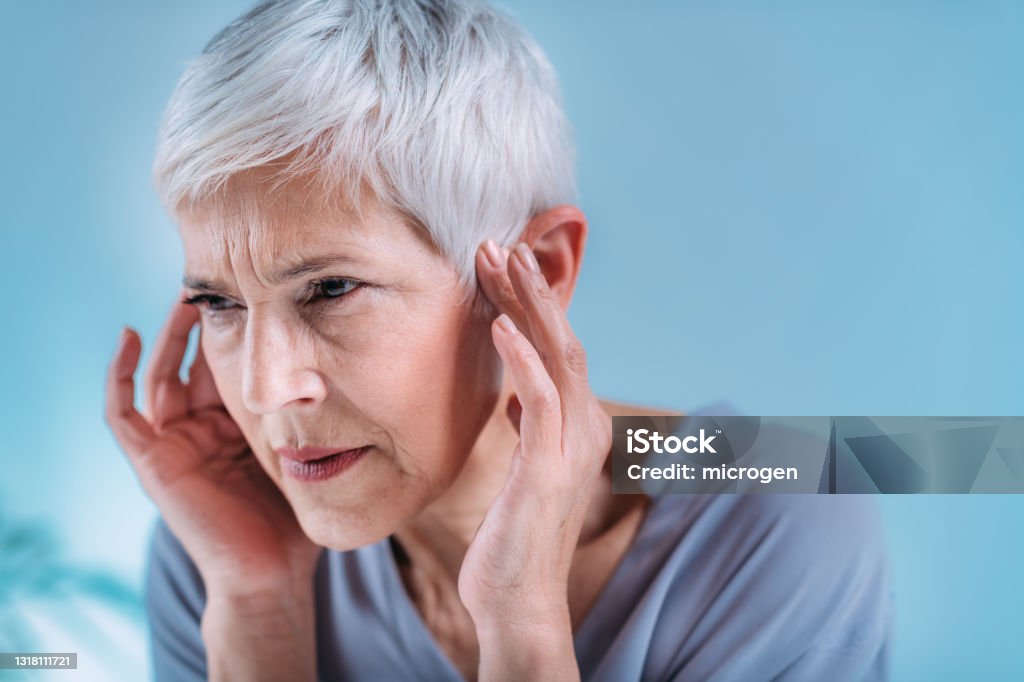 Senior Woman Suffering From Tinnitus Senior woman suffering from tinnitus or ringing in her ears. Tinnitus Stock Photo