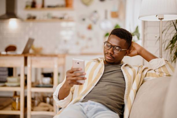 istock Young man using online dating app while relaxing at home. 1318114836