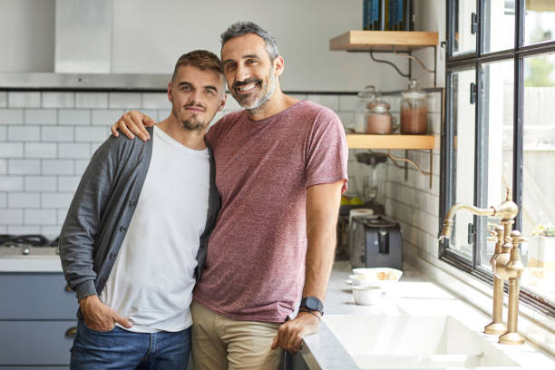 Portrait of happy gay couple at home Portrait of happy homosexual couple at home. Smiling gay men are having spending leisure time together. They are standing in kitchen. queer man facing camera stock pictures, royalty-free photos & images