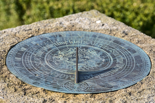 Beautiful closeup view of timekeeping device sundial on stone stand on university campus, Dublin, Ireland. Soft and selective focus