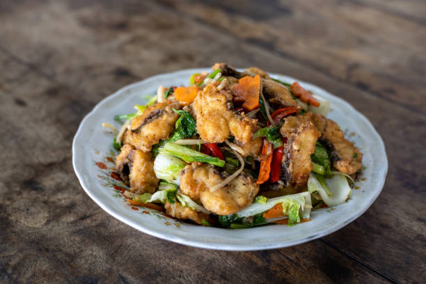 istock Stir-fried fish and vegetables in a plate placed on a wooden table. 1318119148
