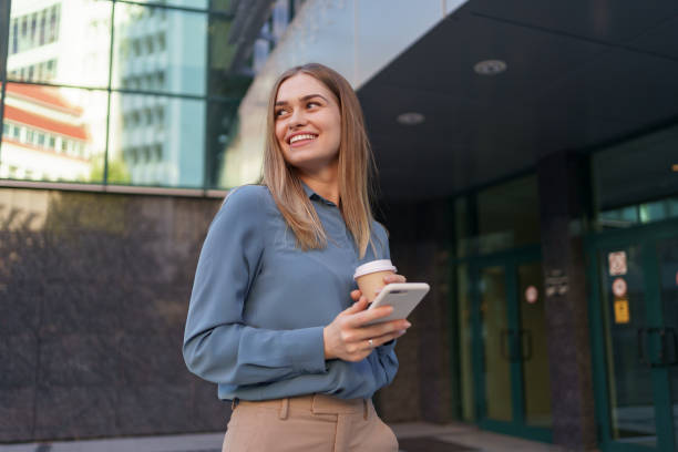 istock Woman using modern smartphone and drinking coffee to go 1318119168