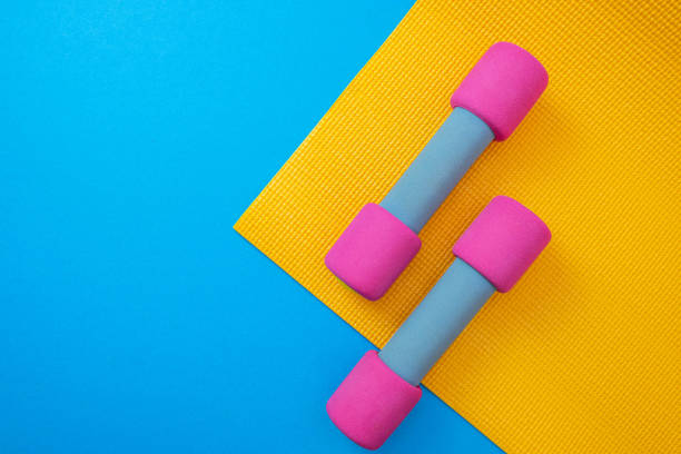 istock yellow mat and pink dumbbells, blue background and close-up 1318121403