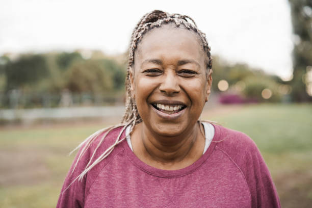 mulher idosa africana sorrindo na câmera ao ar livre no parque da cidade - foco no rosto - women mature adult black american culture - fotografias e filmes do acervo