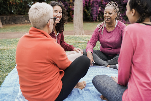 Mujeres multigeneracionales felices divirtiéndose juntas sentadas al aire libre en el parque de la ciudad - Concéntrate en la cara de la tercera edad africana photo