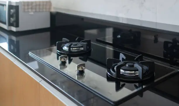 Stainless steel double-head gas stove in the kitchen, on top of the cabinet, placed near me. With electric oven