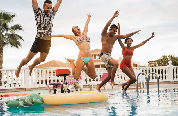istock Multiracial friends having fun jumping inside pool during summer vacation - Main focus on center girl body 1318131074