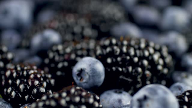 4k dolly video of lots of blackberries and blueberries lying on desk. Perfect abstract background for organic food and healthy nutrition.