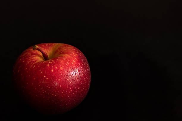 manzana roja madura fresca con gotas de agua sobre cáscara brillante sobre fondo negro - drop red delicious apple apple fruit fotografías e imágenes de stock