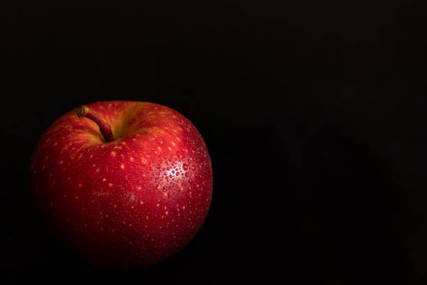 świeże dojrzałe czerwone jabłko z kroplami wody na błyszczącej skórki na czarnym tle - drop red delicious apple apple fruit zdjęcia i obrazy z banku zdjęć