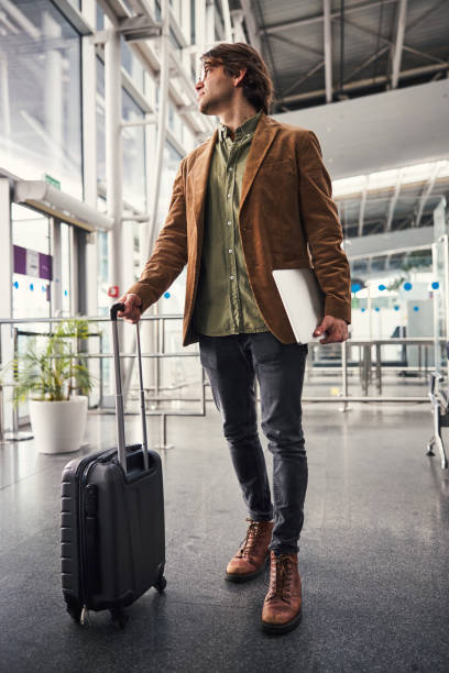 istock Stylish young man with notebook standing in airport terminal 1318135044