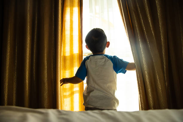 istock baby boy open curtain in bedroom 1318137395