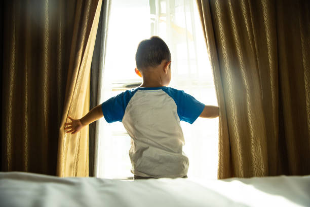 istock baby boy open curtain in bedroom 1318137432