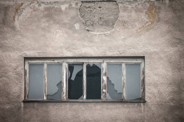 istock Smashed glass on a broken window on an abandoned and decaying factory industrial building left neglected. 1318138330
