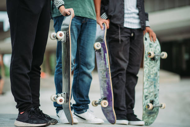 istock Three asian skateboarders standing with hand holding skateboard at skate park 1318138365