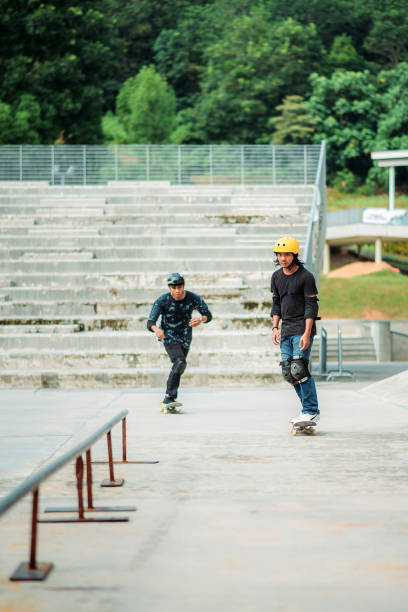 due maschi asiatici che pattinano in uno skate park - extreme skateboarding action balance motion foto e immagini stock