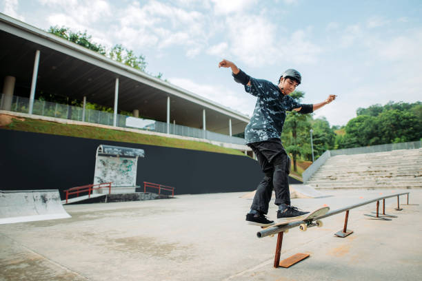 asiatische männliche skateboarding in einem skatepark - extreme skateboarding action balance motion stock-fotos und bilder