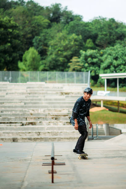 skateboard asiatico maschile in uno skate park - extreme skateboarding action balance motion foto e immagini stock