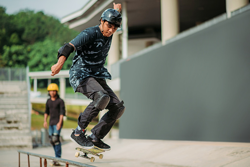 Asian Male Skateboarder Jumping In Air At Skate Park Stock Photo ...