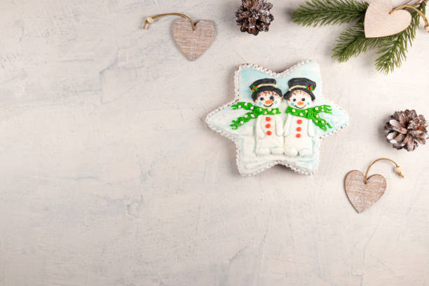 Christmas gingerbread with snowmen on a gray background with fir branches and cones. soft focus