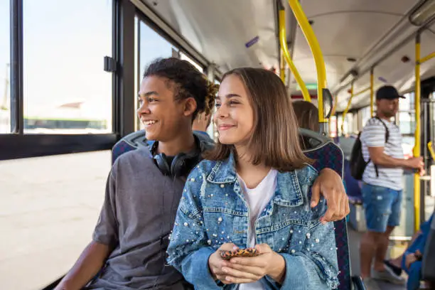 Photo of Teenage couple looking through window in bus